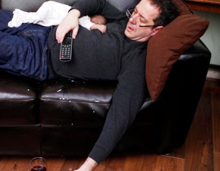 drunk man asleep on sofa with baby lying face down on him