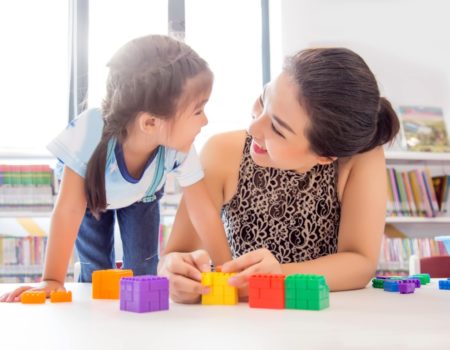 mother playing with daughter at a table