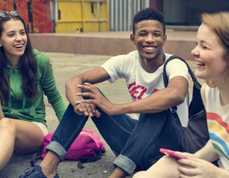 group of teenagers sitting on the floor laughing
