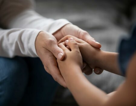 close up of adult and child holding hands