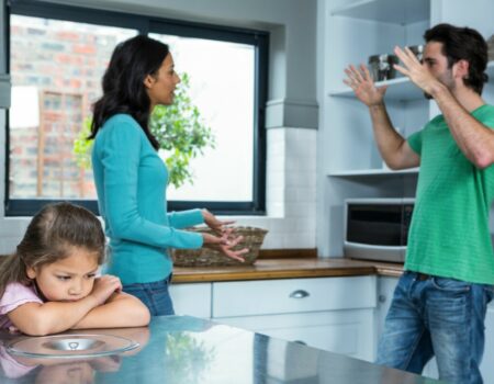 man and woman arguing in kitchen in front of sad little girl